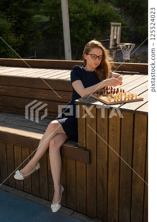 Caucasian woman playing chess outdoors. Caucasian woman playing chess outdoors. 125524023
