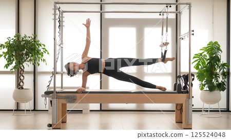 Asian woman doing pilates on reformer. Asian woman doing pilates on reformer. 125524048