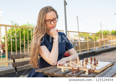 Caucasian woman playing chess outdoors. 125524054