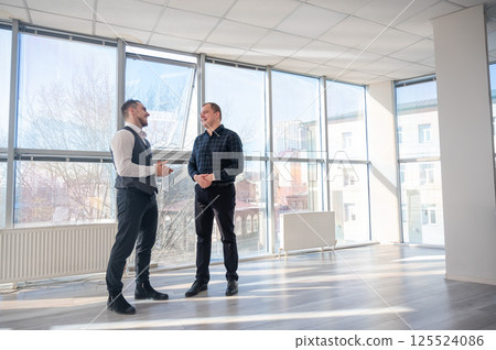 Two Caucasian men talking at work in the office.  125524086