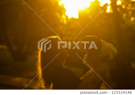 Young Caucasian woman hugging her border collie dog while walking in the park. Young Caucasian woman hugging her border collie dog while walking in the park. 125524146