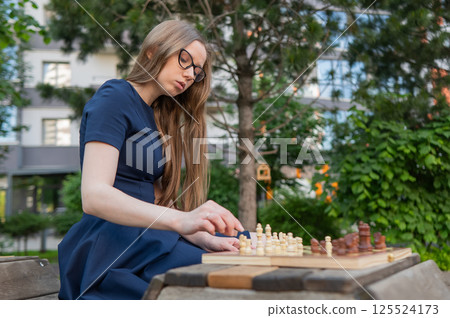 Caucasian woman playing chess outdoors. 125524173