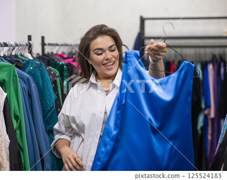 A fat woman chooses clothes in a plus size store.  125524183