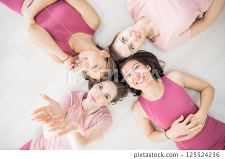 Top view of lying down Two Caucasian and two Asian women in sportswear.  125524236