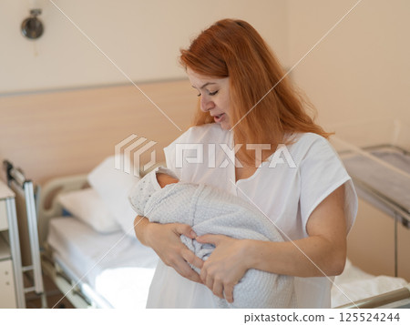 Caucasian woman holding newborn son in maternity hospital ward.  125524244