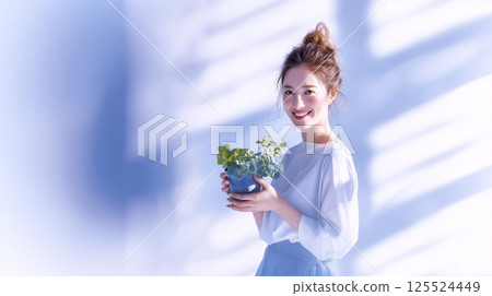 微笑的女人在明亮的窗台旁拿著一盆小盆栽 125524449