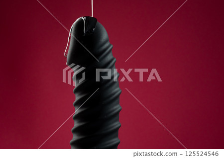 Lube pouring on black dildo on pink background. Lube pouring on black dildo on pink background. 125524546
