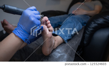 Pregnant woman on a hardware pedicure procedure in a beauty salon. Pregnant woman on a hardware pedicure procedure in a beauty salon. 125524603