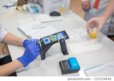 A narcologist tests urine for drugs using an electronic device. A narcologist tests urine for drugs using an electronic device. 125524648