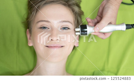 Top view of Caucasian woman undergoing radio wave RF lifting procedure in beauty salon.  125524883