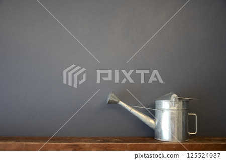 zinc watering can on vintage wooden and wall background 125524987