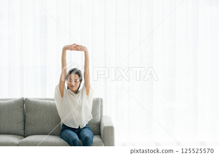 A woman sitting on a sofa and relaxing A woman sitting on a sofa and relaxing 125525570