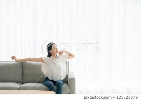 A woman sitting on a sofa and relaxing A woman sitting on a sofa and relaxing 125525579