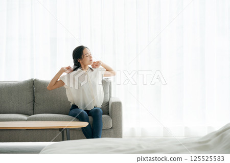 一個女人坐在沙發上和放鬆 一個女人坐在沙發上和放鬆 125525583