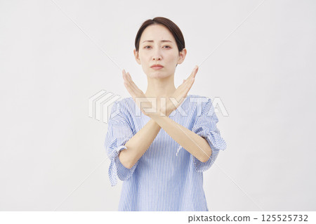 Woman, middle-aged, making a "X" gesture with her arm, white background 125525732