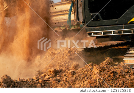 Close-up of excavator at construction site. Backhoe digging soil for earthwork and construction business. Excavating machine at work. Heavy machinery for earth moving and construction site development 125525838