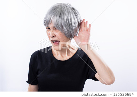 一位年長的女性正專心地聽著,臉上帶著非常不愉快的表情 一位年長的女性正專心地聽著,臉上帶著非常不愉快的表情 125526694