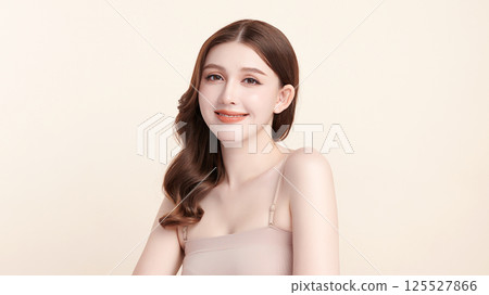 A beautiful young Asian woman with clean, fresh skin against a beige background. Skincare, facial treatment, cosmetology, beauty, and spa. An elegant portrait of an Asian woman. 125527866