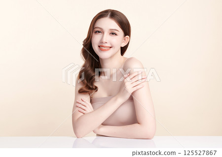 A beautiful young Asian woman with clean, fresh skin against a beige background. Skincare, facial treatment, cosmetology, beauty, and spa. An elegant portrait of an Asian woman. 125527867