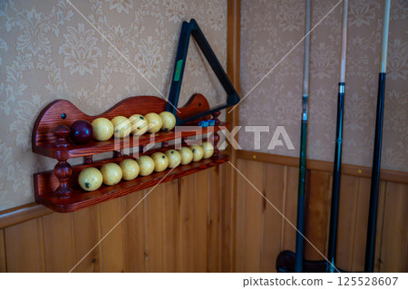 Home billiard setup with white balls, red cue ball, triangle rack, and cues neatly arranged. Concept of indoor recreation and personal hobby space Home billiard setup with white balls, red cue ball, triangle rack, and cues neatly arranged. Concept of indoor recreation and personal hobby space 125528607