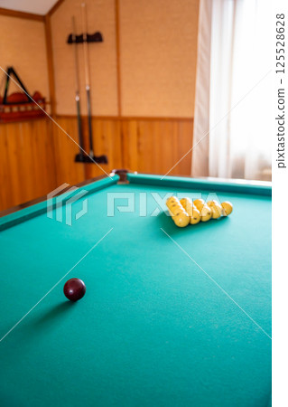 Initial billiard ball arrangement with white balls in a triangle and red cue ball ready for the break. Concept of indoor recreation and personal hobby space Initial billiard ball arrangement with white balls in a triangle and red cue ball ready for the break. Concept of indoor recreation and personal hobby space 125528628