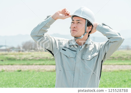 Middle-aged workers, craftsmen and site supervisors in work clothes standing in a rural rice field Middle-aged workers, craftsmen and site supervisors in work clothes standing in a rural rice field 125528788