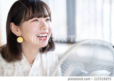 一位身穿浴衣的年輕女子正用扇子納涼 125528855