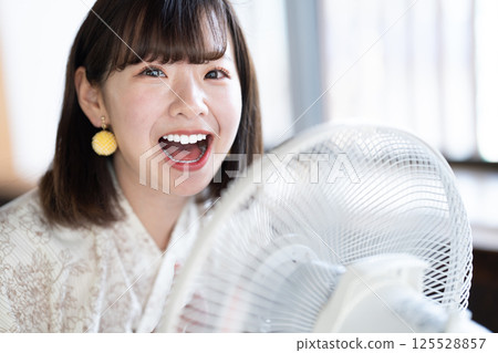 A young woman in a yukata cooling off with a fan 125528857