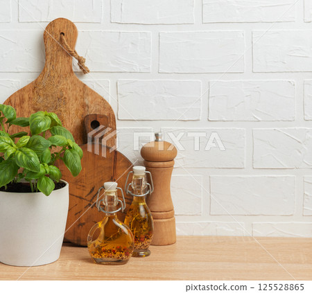 Fresh basil, olive oil, pepper mill and cutting boards resting on kitchen counter 125528865