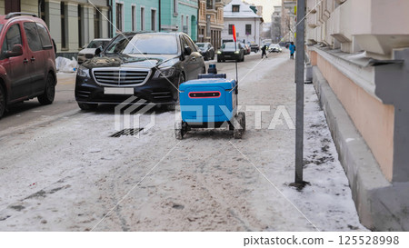 Autonomous delivery robot carrying parcels on snowy city street in Moscow. Autonomous delivery robot carrying parcels on snowy city street in Moscow. 125528998