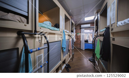 Capsule hotel room showing individual sleeping boxes with ladders providing access 125529002
