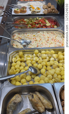 Self-service restaurant offering various dishes including potatoes, rice and fish 125529030