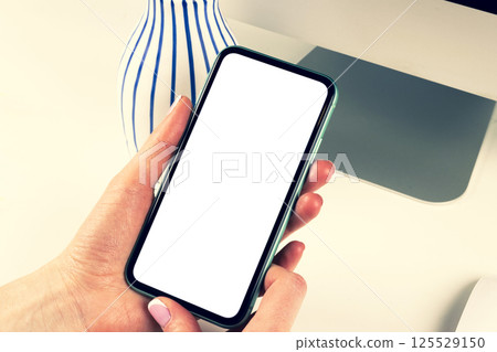 Smartphone mockup in woman hand. New modern black frameless smartphone mock up with blank white screen. Empty space for text. Copy space. Isolated white blank screen. Smartphone mockup in woman hand. New modern black frameless smartphone mock up with blank white screen. Empty space for text. Copy space. Isolated white blank screen. 125529150