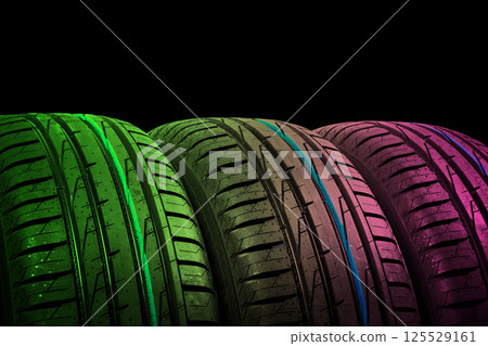 Studio shot of a set of summer car tires in green and pink tones. Tire stack background. Car tyre protector close up. Black rubber tire. Brand new car tires. Close up tyre profile. Car tires in a row 125529161