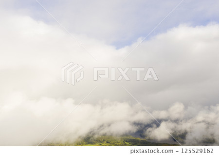 Aerial view clouds over the forest and lake. View from drone. Aerial top view cloudscape. Texture of clouds. View green forest from above covered with white clouds 125529162