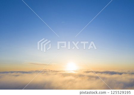 Aerial view gold sunrise over clouds in blue sky. Aerial top view cloudscape. Texture of clouds. View from above. Orange sunrise or sunset over clouds. Panorama clouds texture 125529195