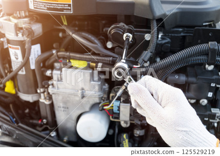 Repairing outboard marine engine. Motorboat engine seasonal service and maintenance. Mechanic yfnd performing maintenance on outboard engine Repairing outboard marine engine. Motorboat engine seasonal service and maintenance. Mechanic yfnd performing maintenance on outboard engine 125529219