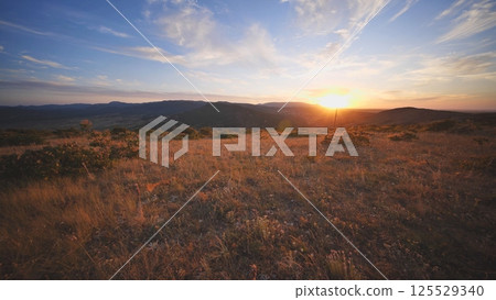 Sunset illuminating dry Crimean steppe landscape with hills and meadows Sunset illuminating dry Crimean steppe landscape with hills and meadows 125529340