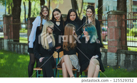 High school students gather on benches in schoolyard during break, chatting and enjoying each other's company 125529352