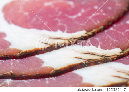 Top view of smoked pork salami chorizo sausages slices background. Raw smoked salami pattern 125529447