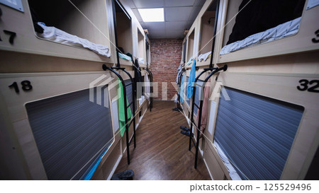 Rows of capsule beds in modern hostel dormitory offering comfortable and affordable accommodation 125529496