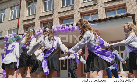 Happy graduates wearing purple ribbons perform a traditional dance outside their high school on the final day of classes Happy graduates wearing purple ribbons perform a traditional dance outside their high school on the final day of classes 125529497