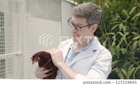Happy veterinarian doctor man holding examining chicken for health care, farmer hold hen in natural eco farm, Animal care and ecological farming concept Happy veterinarian doctor man holding examining chicken for health care, farmer hold hen in natural eco farm, Animal care and ecological farming concept 125529693