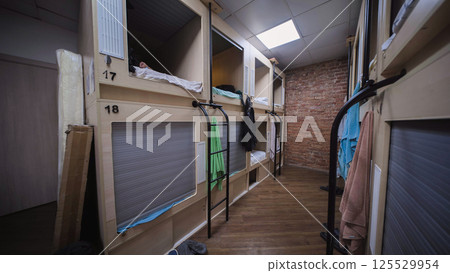 Hostel guest sleeping in pod bed with privacy rolling shutter door 125529954