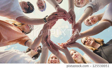 Students joining hands in a circle, representing teamwork, camaraderie, and solidarity 125530051