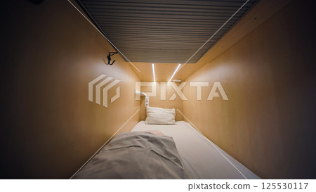 Compact capsule hotel room inviting guests for comfortable sleeping 125530117