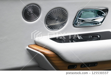 Door handle with power window control buttons of a luxury passenger car. White perforated leather interior with stitching and natural wood panel. Modern car interior details. Car detailing. Car inside Door handle with power window control buttons of a luxury passenger car. White perforated leather interior with stitching and natural wood panel. Modern car interior details. Car detailing. Car inside 125530337