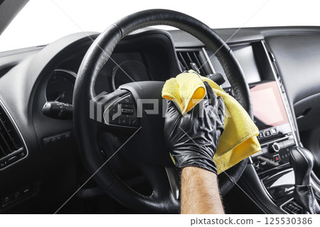 A man cleaning car with yellow microfiber cloth. Car detailing or valeting concept. Selective focus. Car detailing. Cleaning with sponge. Worker cleaning. Car wash concept solution to clean A man cleaning car with yellow microfiber cloth. Car detailing or valeting concept. Selective focus. Car detailing. Cleaning with sponge. Worker cleaning. Car wash concept solution to clean 125530386