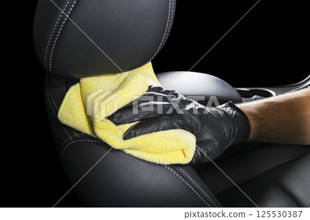 A man cleaning car seat with yellow microfiber cloth. Car detailing or valeting concept. Selective focus. Car detailing. Cleaning with sponge. Worker cleaning. Car wash concept solution to clean A man cleaning car seat with yellow microfiber cloth. Car detailing or valeting concept. Selective focus. Car detailing. Cleaning with sponge. Worker cleaning. Car wash concept solution to clean 125530387