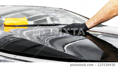 A man cleaning car with microfiber cloth. Car detailing or valeting concept. Selective focus. Car detailing. Cleaning with sponge. Worker cleaning. Car wash concept solution to clean A man cleaning car with microfiber cloth. Car detailing or valeting concept. Selective focus. Car detailing. Cleaning with sponge. Worker cleaning. Car wash concept solution to clean 125530416